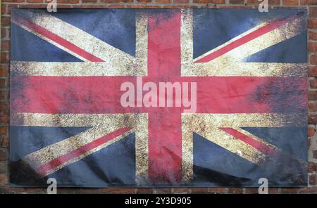 An old stained dirty union jack british flag with dark crumpled edges on a brick wall background Stock Photo