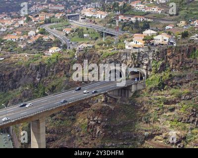 An aerial landscape view of the motorway bridge in funchal entering a tunnel in the valley with buildings and streets of the city Stock Photo