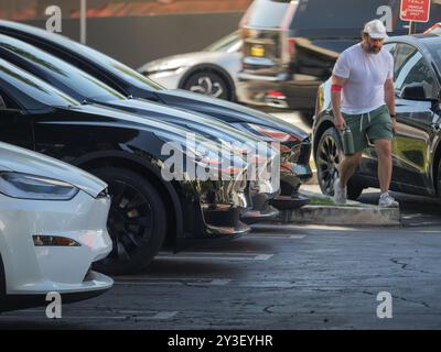 LOS ANGELES, CA - June 25, 2024: Tesla electric cars lined up in a row, charging at Tesla Supercharger charging station at 8775 Sunset Boulevard, WeHo Stock Photo