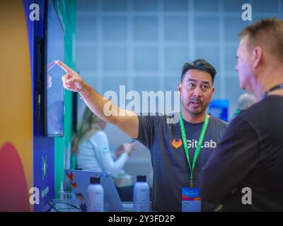 LOS ANGELES, CA- May 22, 2024: Company representative presenting GitLab software product to a prospective customer on computer screen at AWS Summit in Stock Photo