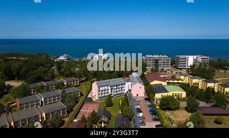 A drone view of Darłowo’s golden sandy beach with sunbathers relaxing and swimmers enjoying the calm Baltic Sea. Nearby hotels line the coast. Stock Photo