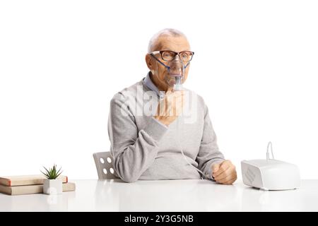 Senior man sitting and using a nebulizer isolated on white background Stock Photo