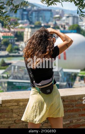 Tbilisi, Georgia - 12 AUG, 2024: Young woman taking photos of the Rike Park in the center of Tbilisi, Georgia. Stock Photo