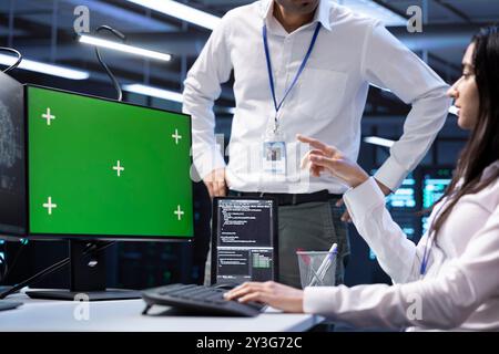 Software developers doing checkup on green screen computer in server room used for artificial intelligence workloads. IT staff members inspecting neural network data center facility with mockup PC Stock Photo