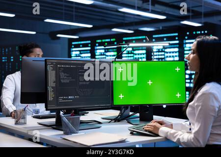 Specialists using green screen PC to check server clusters configuration settings. Engineers checking event logs in monitoring software to find faulty data center hardware root cause Stock Photo