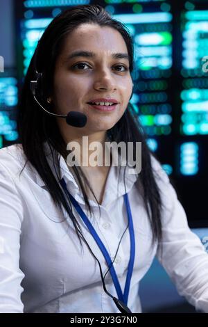 Upbeat supervisor in data center providing support for customers, troubleshooting malfunctions. Portrait of cheerful employee in server room carrying out operational interventions requested by clients Stock Photo