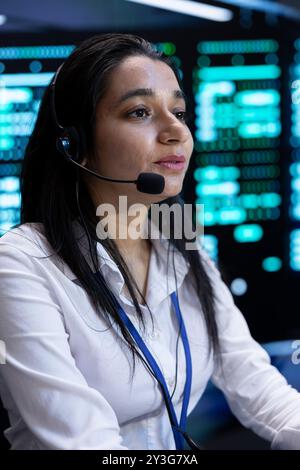 Data center call center admin responsible for providing logistics support to customers. Woman in server hub overseeing infrastructure systems and communicating with engineers Stock Photo
