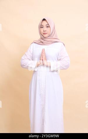 Asian woman wearing beautiful elegant Muslim dress poses with arms crossed isolated on cream background. beauty, model, studio and fashion concept Stock Photo