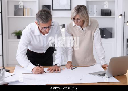 Architects making engineering drawing at wooden table in office Stock Photo