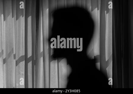 Hidden Identity: Blurry Silhouette Against Curtains in Black and White. Stock Photo