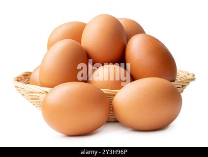 Group of fresh brown chicken eggs in stack in wicker basket is isolated on white background with clipping path. Stock Photo