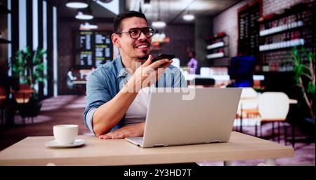 Man Drinking Coffee And Working On Laptop. Sending Voice Message On Phone Stock Photo
