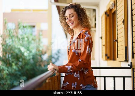 Cheerful young woman standing on balcony Stock Photo