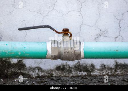 Close-up of plumbing pipe and valve on house rooftop, with a water system set against an old cement wall background. Stock Photo