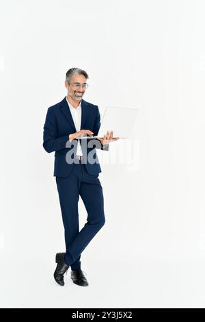 Happy mature business man using laptop standing isolated on white background. Stock Photo
