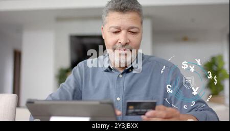 Image of currency icons and data over biracial man paying online with card Stock Photo