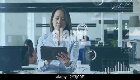 Image of financial data processing over biracial businesswoman using tablet in office Stock Photo