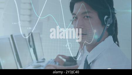 Image of financial data processing over asian businessman using phone headset and computer Stock Photo
