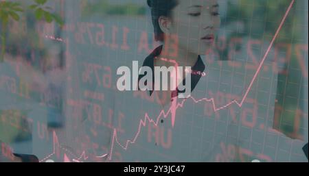 Image of financial data processing over asian businesswoman using computer Stock Photo