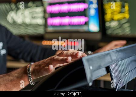Close-up of music producer's hands working on professional audio equipment in recording studio. Digital audio workstation setup with multiple monitors Stock Photo