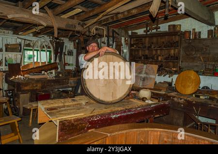 Cultra County Down Northern Ireland September 2024 - Man wearing a flat cap in an old workshop carving a barrel lid as a retirement present Stock Photo