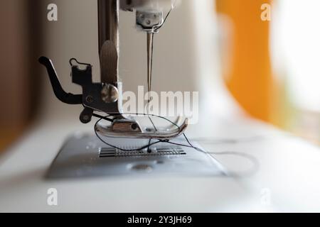 Detailed close-up of a sewing machine needle with fabric threaded through, capturing the essence of sewing. Stock Photo