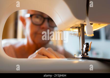 Close-up of a sewing machine in action, with focus on the needle and fabric, highlighting the sewing process. Stock Photo