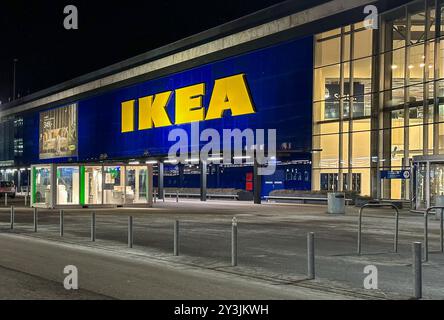 Nighttime view of an IKEA store with bright yellow signage on a blue facade, showcasing the iconic design of one of the world's largest furniture reta Stock Photo