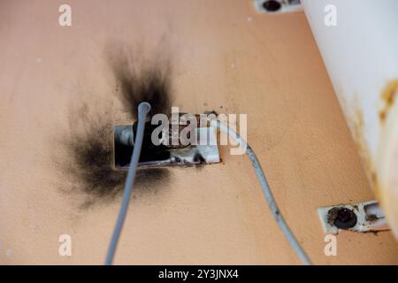 A burnt electrical outlet with visible black soot marks, showing signs of a short circuit or electrical malfunction, posing a potential fire hazard Stock Photo