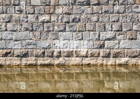 Old stone wall with water reflection in the canal Stock Photo