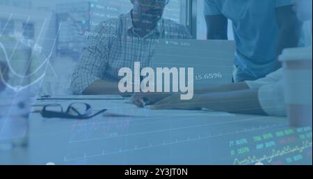 Image of financial data processing over diverse business people using laptop Stock Photo