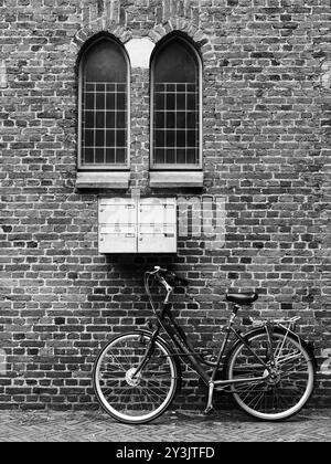 Symmetrical lines of a bicycle parked next to a church under a mailbox with free space Stock Photo