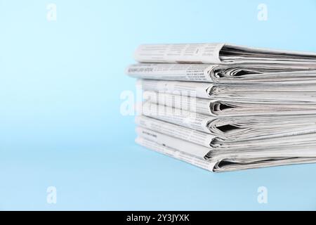 Stack of newspapers on light blue background, space for text Stock Photo