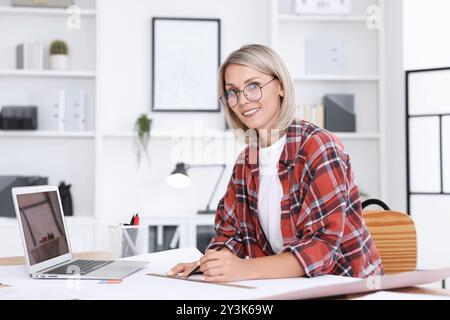 Architect making engineering drawing at table in office Stock Photo