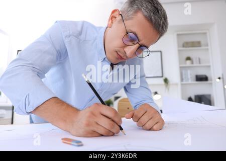 Architect making engineering drawing at table in office, low angle view Stock Photo