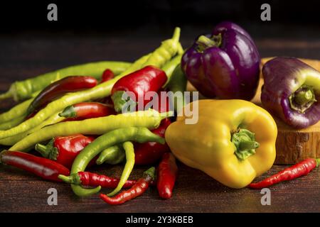 Colourful peppers and chillies arranged on a dark wooden surface, food photography Stock Photo