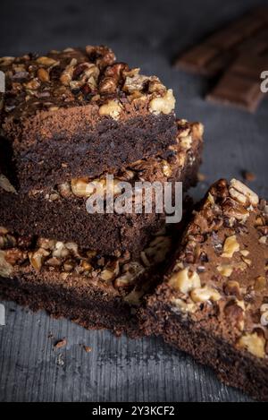 Delicious brownies with walnuts, in a stack on a wooden table. Close-up image with brownie cake sliced pieces Stock Photo