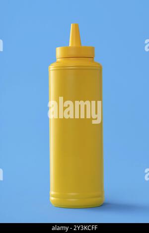 Mustard plastic bottle isolated on a blue colored background Stock Photo