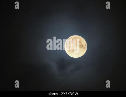 Glowing full halloween november moon surrounded by illuminated clouds Stock Photo