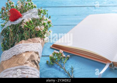 Woman blue wooden desk with a bouquet of tiny white flowers and an open notepad. Mothers day frame. Spring context. Valentine day gift Stock Photo