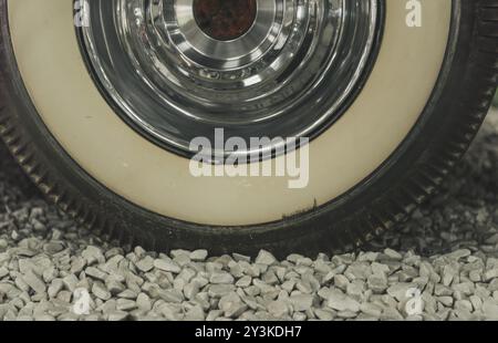 Close up with the wheel from an old timer car, details on the aged tire and the shiny chrome rim Stock Photo