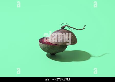 Sliced beetroot minimalist on a green table. Red beet sliced in half, isolated on a colorful background Stock Photo