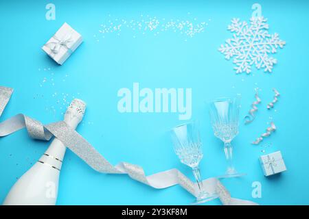 Flat lay composition with confetti and bottle of sparkling wine on light blue background, space for text. Christmas decor Stock Photo