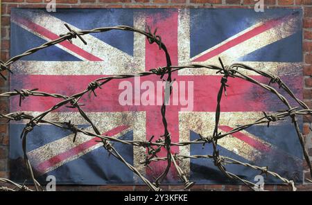 Barbed wire in front of an old stained dirty union jack british flag with dark crumpled edges on a brick wall background brexit freedom of movement is Stock Photo