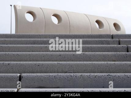 Grey textured outdoor concrete stairs with geometric curved wind shelter in Cleveleys, Lancashire Stock Photo