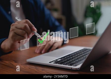 A businessman interacts with a digital checklist on a laptop, symbolizing task management and efficiency in a modern office. Stock Photo