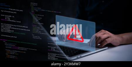 Hands typing on a laptop keyboard with a red warning symbol displayed on a virtual interface, indicating a cybersecurity threat or system error code Stock Photo