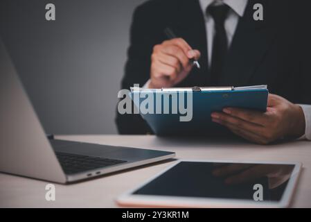 Businessman reviewing report on clipboard. Focus on analysis, data evaluation. Ideal for business, corporate, presentations. Professional, realistic s Stock Photo