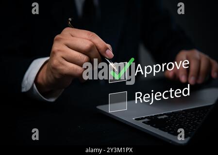 Hand with a pen marking approval on a digital checkbox laptop. management processes, corporate evaluations. Perfect for business approval workflows, q Stock Photo