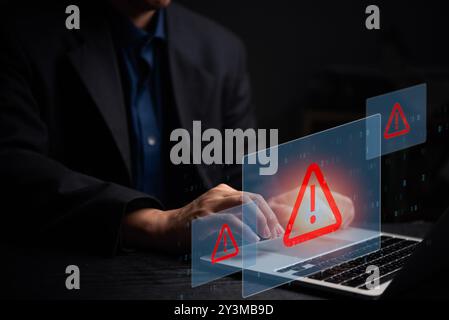 Man typing on laptop with floating red warning icons. Represents cybersecurity threats, data protection, and digital risk management, emphasizing caut Stock Photo
